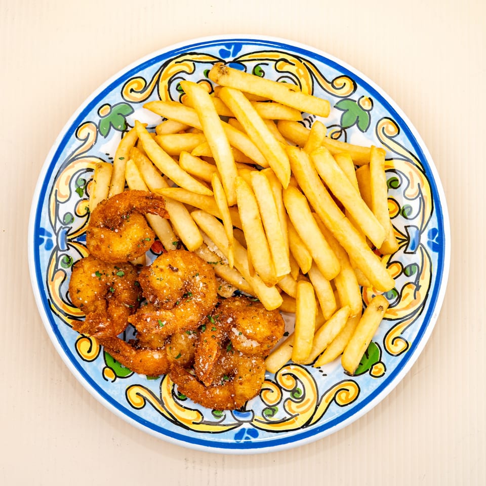 Golden fried shrimp and french fries on a colorful, patterned plate from All Star Pizza.