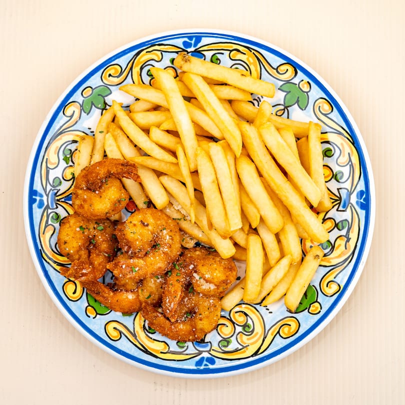 Golden fried shrimp and french fries on a colorful, patterned plate from All Star Pizza.