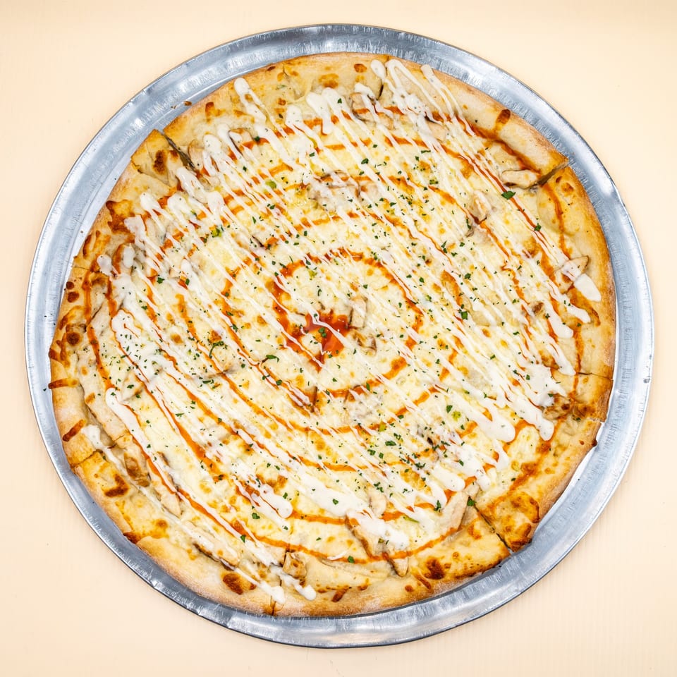 All Star Pizza's chicken pizza with white and orange sauce swirls, topped with parsley, on a metal pan.