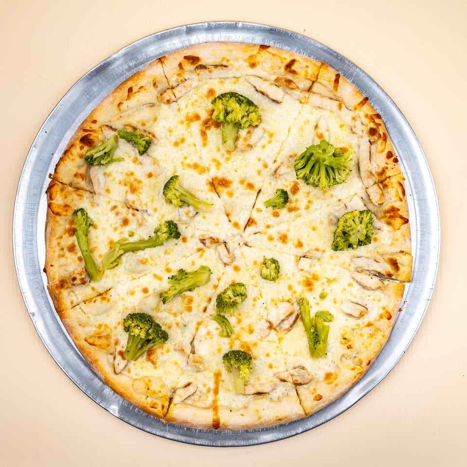 All Star Pizza's white pizza with chicken and broccoli, served on a metal pan.